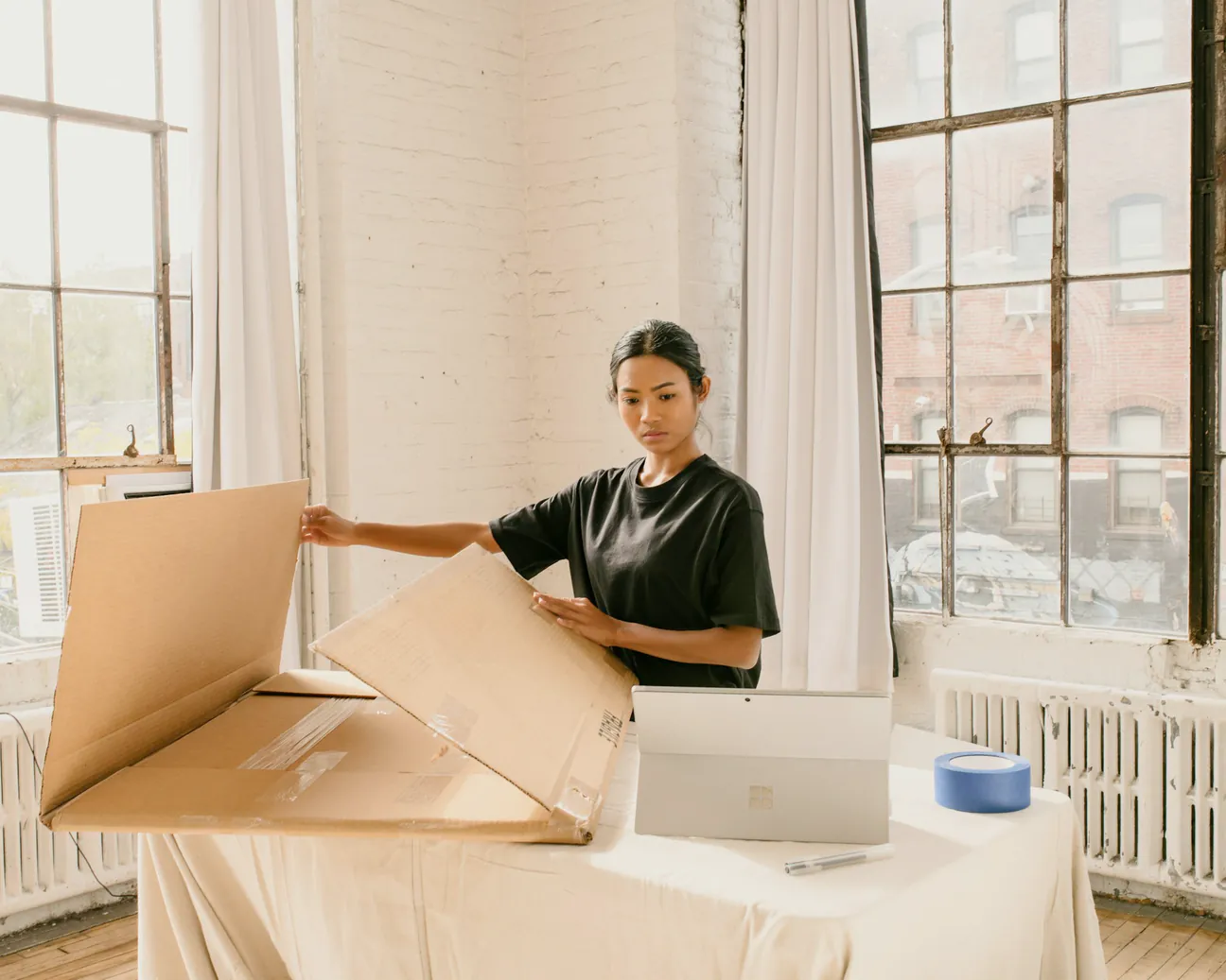 A woman preparing a cardboard box for packing at home